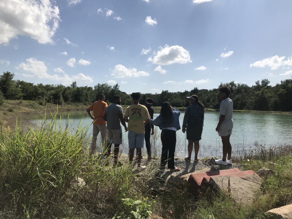 group of adults standing near large pond in a sunny day