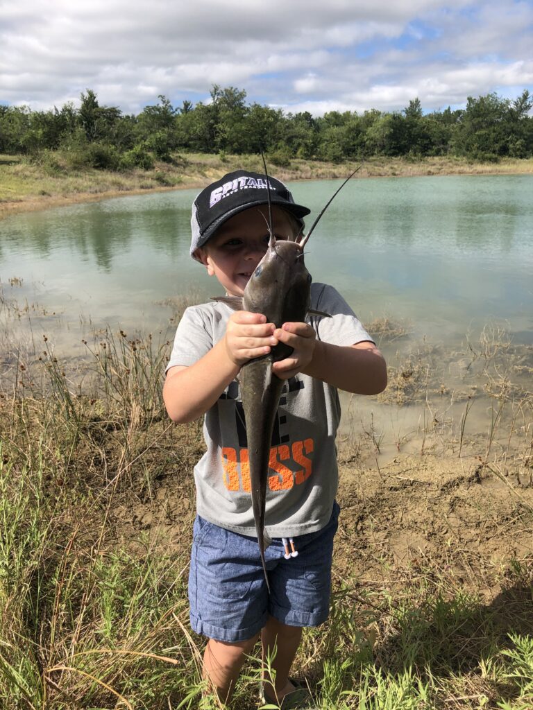 little boy in black ht holding fish